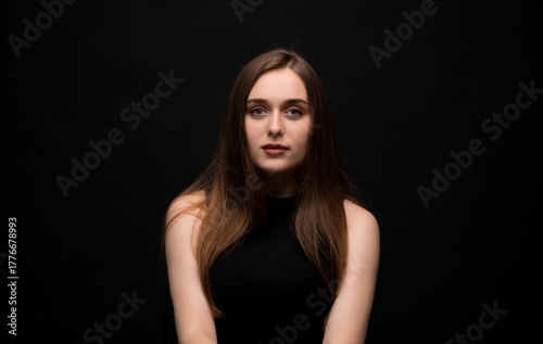 Confident young woman showing thumbs up and smiling slightly on blue background