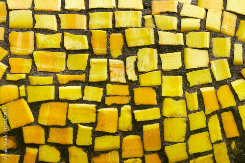 A fragment of a street mosaic made of yellow smalt on cement mortar.