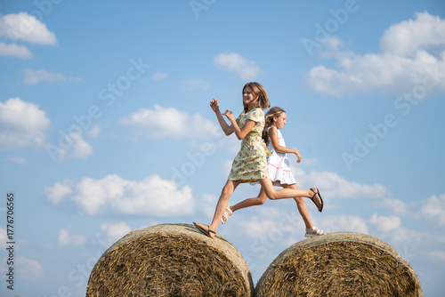 Obraz na plátne Two young girls, one in a floral dress and the other in a white dress, joyfully