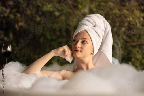 mulher jovem relaxando sozinha na banheira, banho de espuma e sais spa
