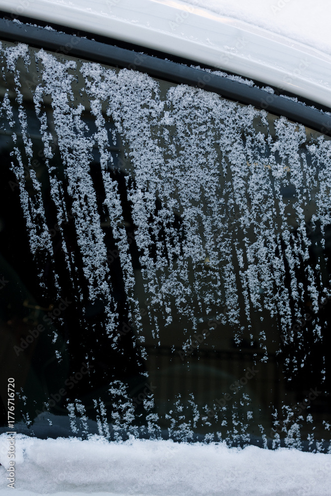 Obraz premium Frozen snow covers car window while streaks show where it has been scraped off on a cold winter morning