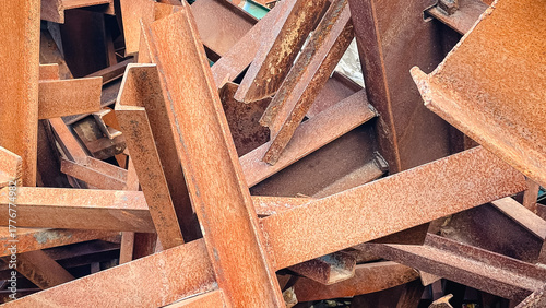 Close-up of a chaotic pile of heavily rusted metal I-beams, creating an industrial abstract background texture