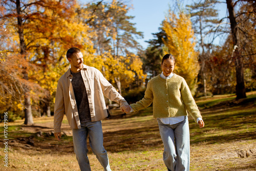 Φωτογραφία Korean woman and Caucasian man enjoy a delightful autumn stroll in a vibrant par
