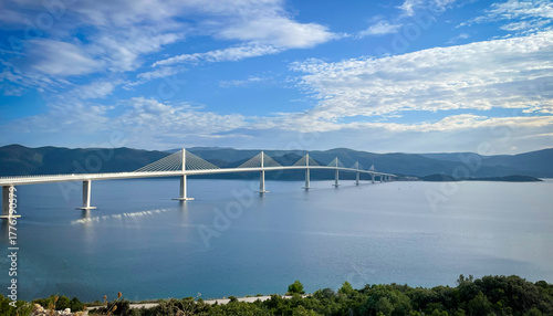 Panoramic view of the Peljesac Bridge spanning the Adriatic Sea channel in southern Croatia. Modern cable stayed bridge glows in soft sunlight, connecting Croatian mainland to Peljesac Peninsula.