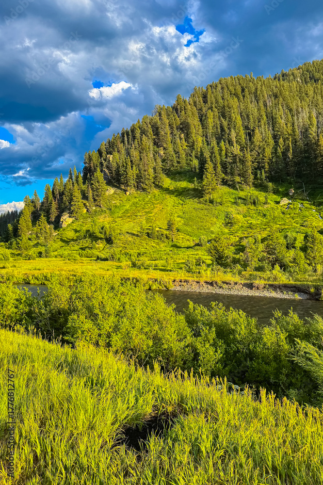 Obraz premium Captivating mountain landscape with lush greenery and a serene river under a vibrant sky in the late afternoon