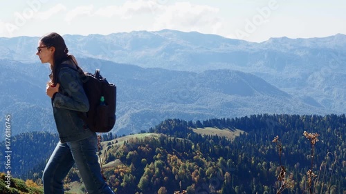 Walking in the mountains, hiking. A young woman with a backpack walks forward against the background of mountains