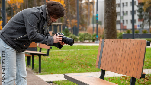 Woman Capturing Unique Photographs of an Empty Park Bench on a Cool Autumn Day in the City