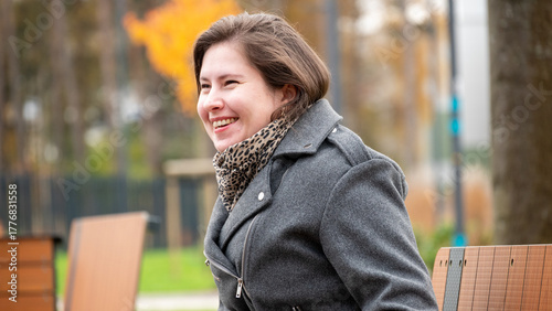 Smiling Woman Enjoys Autumn Day in Park, Showcasing Joy and Warmth in Her Casual Outdoor Outfit