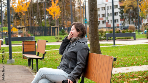 Young Woman Sits on a Park Bench Enjoying the Autumn Scenery and Fresh Air in a Vibrant Urban Park