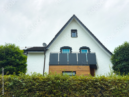 Charming modern house nestled among lush green hedges on a cloudy day