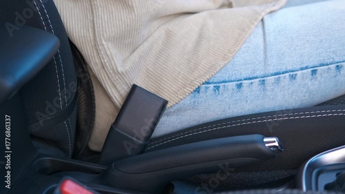 Woman fastening seat belt in car. Female driver carefully securing seatbelt inside vehicle, highlighting personal safety and responsible driving practices before beginning journey