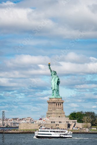 The Statue of Liberty stands tall against a vibrant blue sky filled with dramatic clouds in New York City.