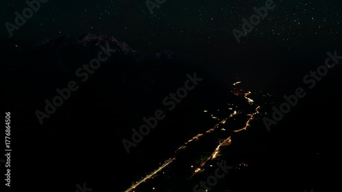 A stunning timelapse sequence of mountain scenery shifting from sunset to night. Night aerial view of illuminated roads