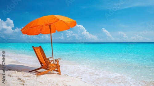 A wooden chair sits on the sandy beach under a vibrant orange umbrella facing clear turquoise waters.