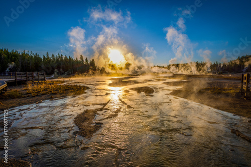 Sunrise light shining through steam at Norris Geyser Basin, Yellowstone National Park, Wyoming, USA, with vivid geothermal colors.