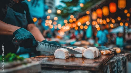 Fototapeta Naklejka Na Ścianę i Meble -  Chef wearing black gloves slicing thick pork belly on wooden board on festive lights background