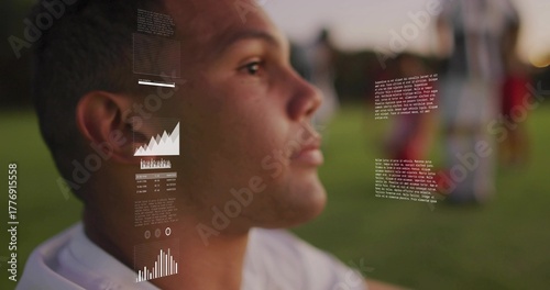 Male soccer player wearing white jersey analyzing data overlays on grass pitch at dusk, copy space