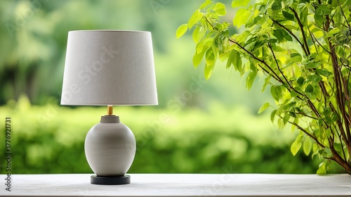 Ambient Light: A stylish lamp sits on a sleek surface with a backdrop of lush foliage, casting a gentle illumination, perfect for creating a warm and inviting atmosphere.