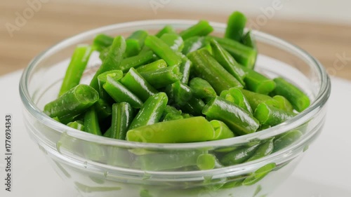 Fried wok green beans with onions and spices in a white plate on a gray background. Flat lay. Top view.