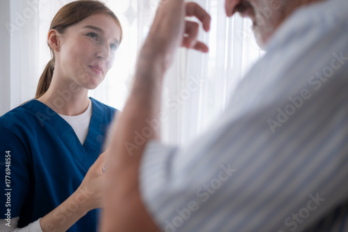 An elderly man and his doctor, standing by the window in the patient room