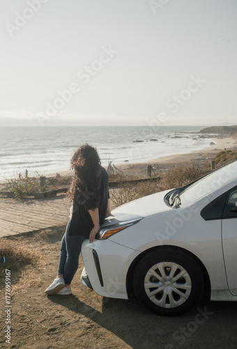 California coast lifestyle – Latina woman relaxing by her car watching the sea during a trip.