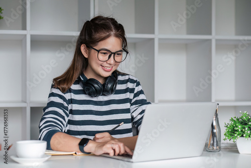 Asian female student study online in class, study online, wearing headphones, watching video call, zooming, happy asian female learning language online with computer laptop.