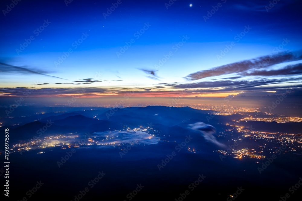 Fototapeta premium Twilight Over Mountain Silhouettes with City Lights and Celestial Glow