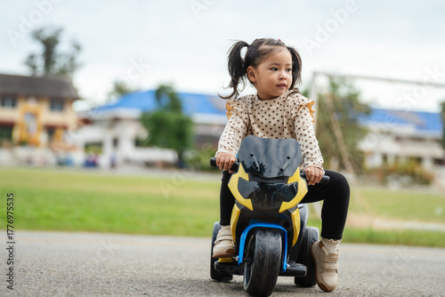 toddler girl riding an electric motorcycle toy in park