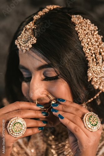 Bridal jewelry closeup featuring ornate gold accessories, green gemstone rings, and elegant hand detail showcasing luxury Indian wedding fashion and cultural craftsmanship.