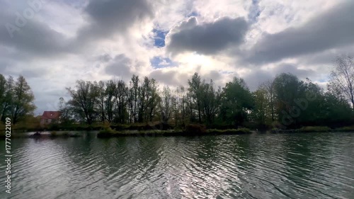 Chaotic sky above rippling reflective river, Powerful cloud formations over fluctuating river reflections create tension
