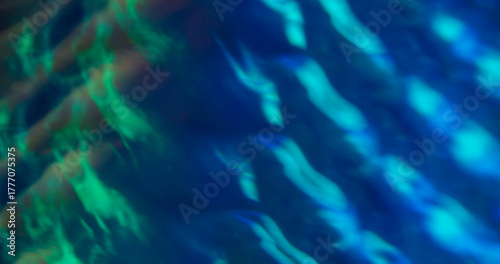 Defocused illumination overlay. Colorful flare. Blue green glossy wavy texture. Neon luminosity abstract kaleidoscopic background.