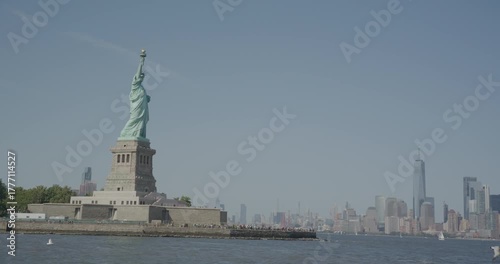 Beautiful lady liberty on island with view of Manhattan behind as seagull flys by - slow motion