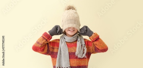 Cute little boy in winter clothes on beige background