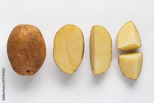 Fotografie Overhead view of a whole raw potato beside slices and wedges of potato, showing the inner yellow flesh, isolated on a white background