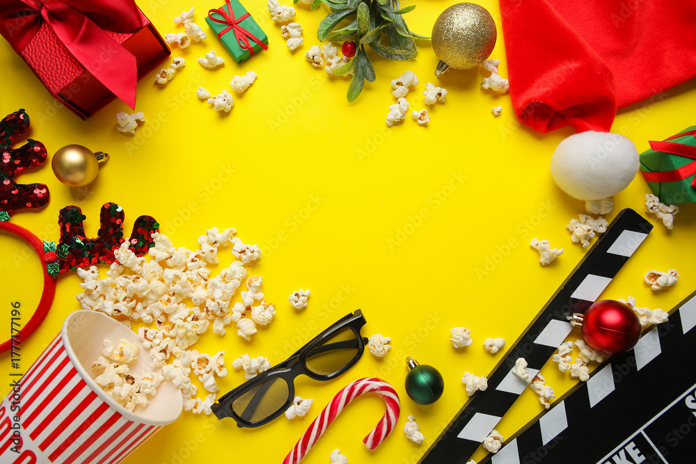 Obraz premium Frame made of popcorn, movie clapper, 3D glasses, gifts and decorations on yellow background. Christmas movie