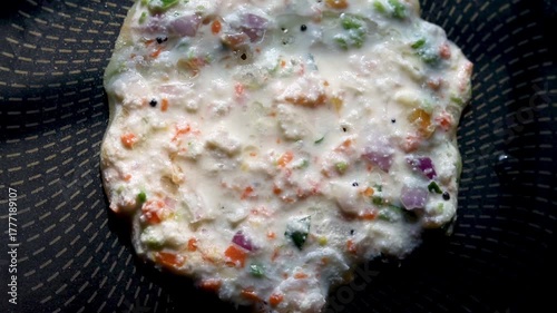 Indian chilla or uttapam prepared on black pan in kitchen with sunlight
