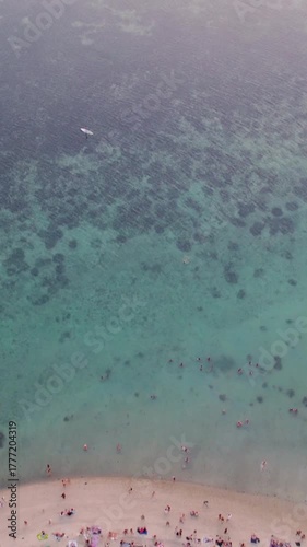 vertical.Drone sunset shot of crowds of people dancing and having fun on a zen beach, and ocean island Koh-Phangan