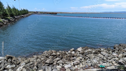 Calm Blue Water Separated by Rocks and Trees Under a Clear Sky