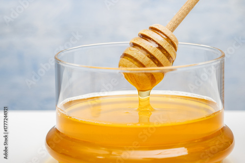 Honey background. Sweet honey in the glass jar. Light gray background.text.