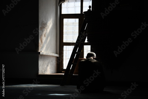 Dramatische Silhouette einer Person im Lichtkegel eines Fensters