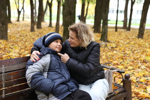 A woman meets her son in the park on a beautiful autumn day.