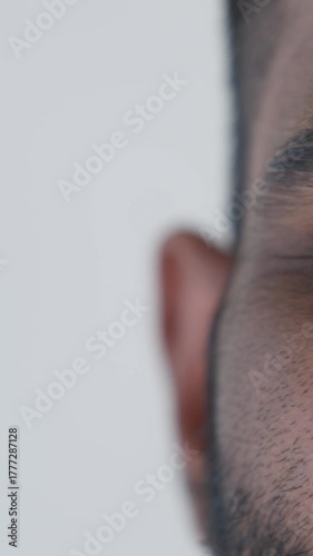 Vertical video. Close-up of a man's eye and tense face showing fear and worry as he stares at the camera, conveying anxiety and concern after troubling medical news in a clinical setting
