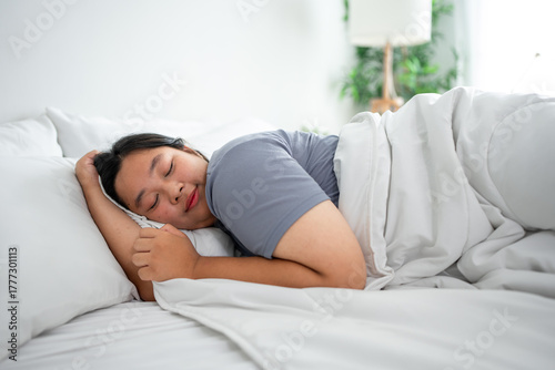 Asian plus-size woman in pajamas sleeping in the morning with happiness