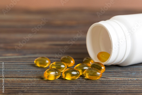 Soft gels pills with Omega-3 oil spilling out of pill bottle close-up. Gel capsules bottle white surface. Omega 3, multivitamins, Calcium, antibiotics. Health. Immunity