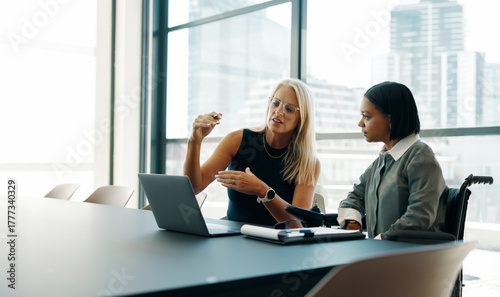 Two businesswomen discussing plans in a modern office setting