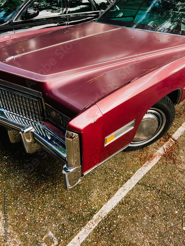 Tableau sur toile Close up view of a burgundy vintage car parked in parking lot, showcasing its shiny hood, chrome grill, and iconic design elements, evoking sense of nostalgia for classic automobiles