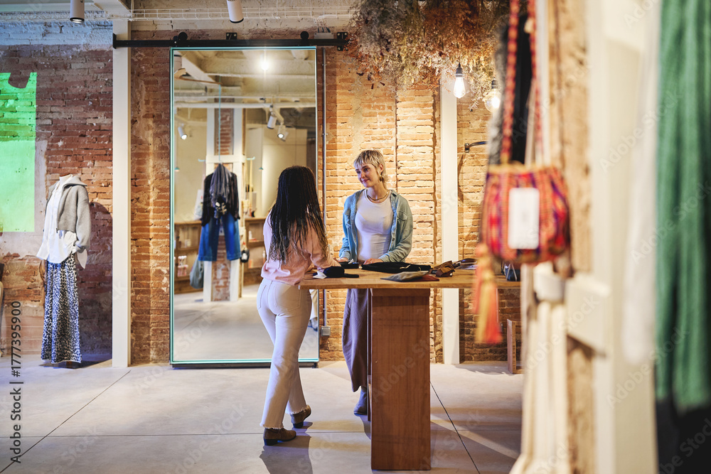 Fototapeta premium Women talking and shopping together inside stylish boutique store