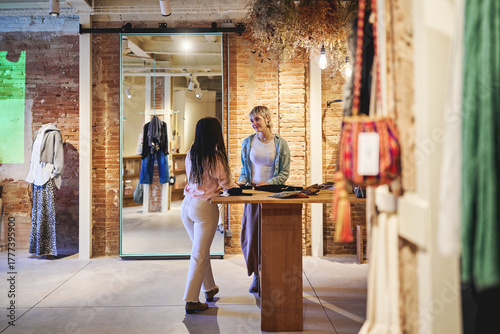 Women talking and shopping together inside stylish boutique store
