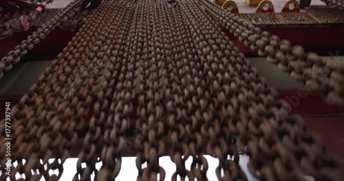 Old metal chains hang waving in wind on transport ship beam low angle shot. Freights fastening equipment in marine dock. Connected links