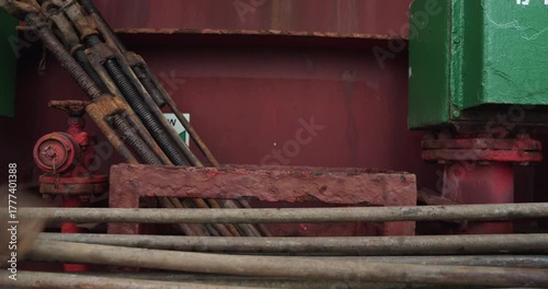 Worker in gloves collects weathered metal fastening items in holder on deck closeup. Sailor arranges huge eye bolts working on ship vessel